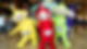 Four colorful Teletubbies mascots pose and smile in a mall beneath a Teletubbies sign, bright and playful.