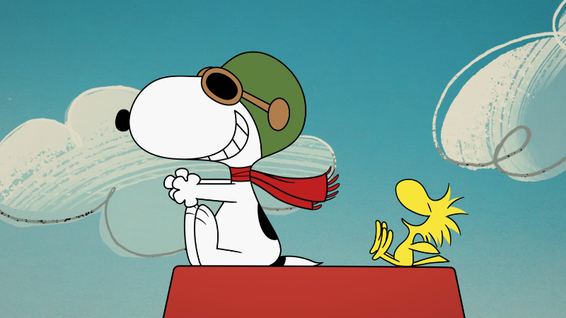 Snoopy in aviator helmet and red scarf sits on a red doghouse with Woodstock against a blue sky with clouds.