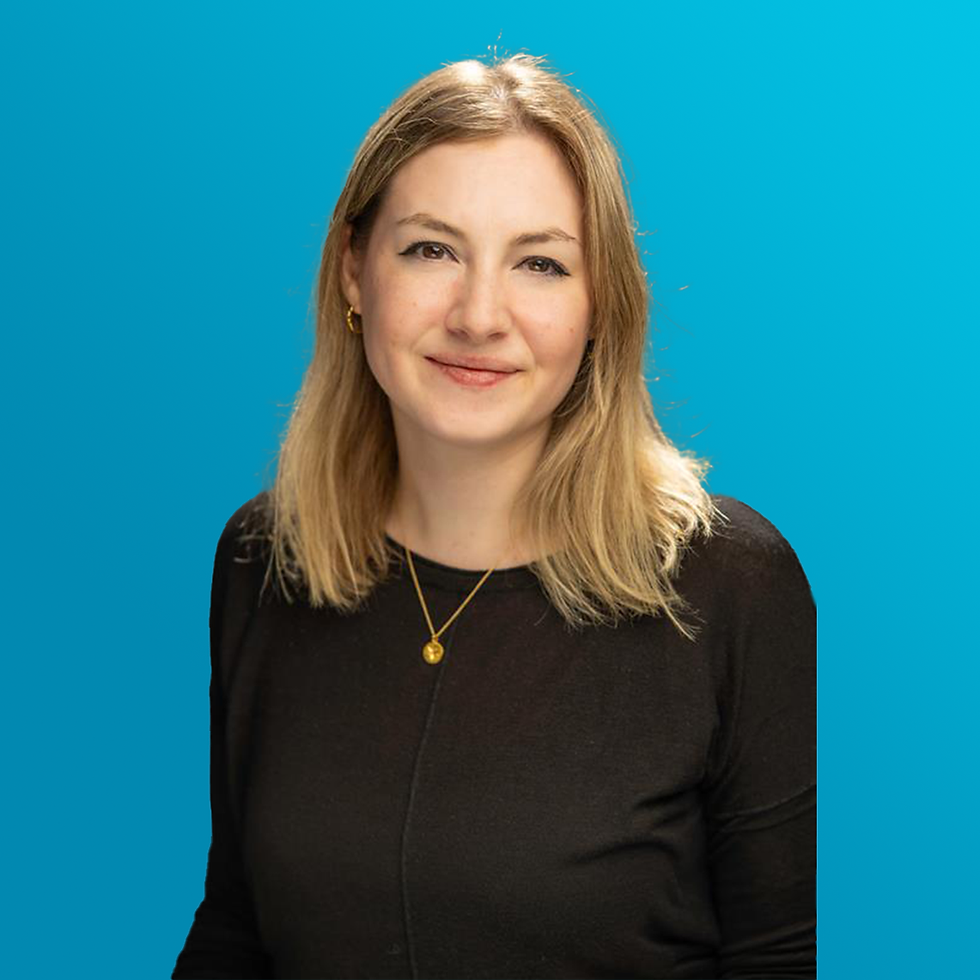 Danielle Tanton wearing a black shirt is posing in front of a blue background