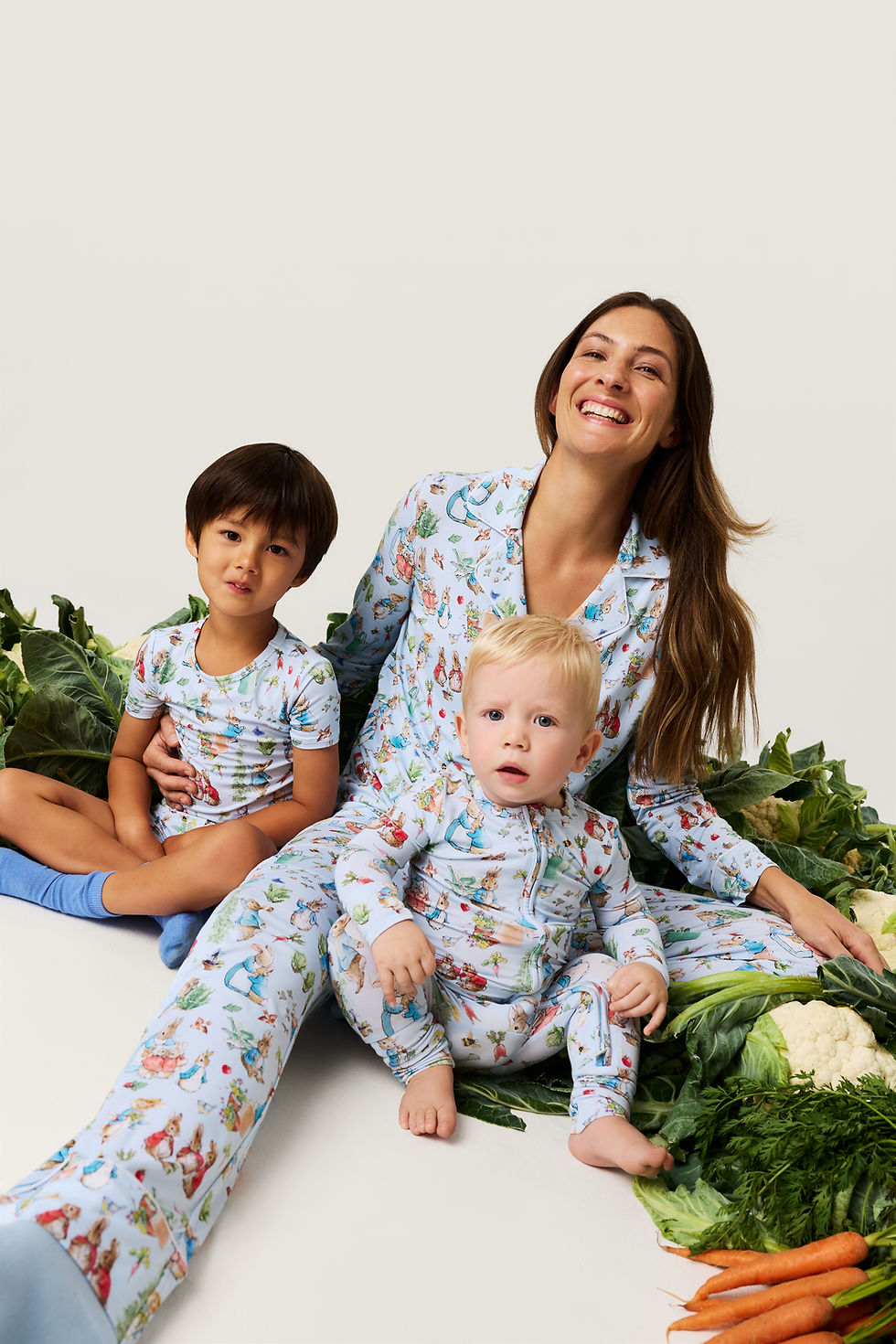 A woman holding two young children, all wearing the clothes from the Peter Rabbit Posh Peanut collection