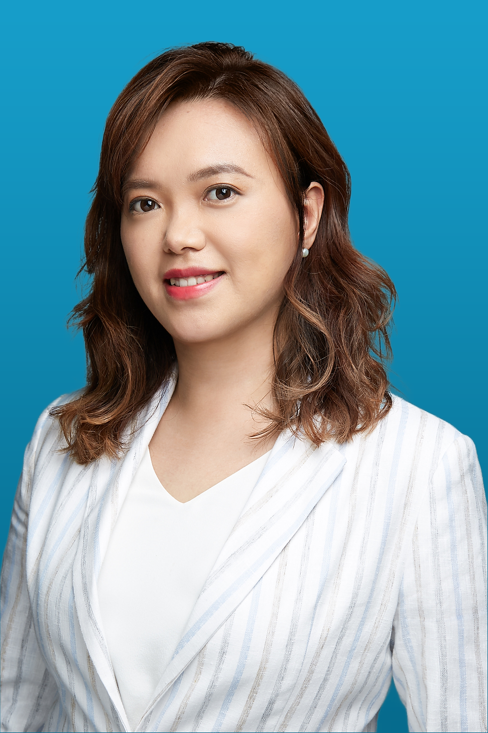 Evi Sari is wearing a white suit and is posed in front of a blue background.