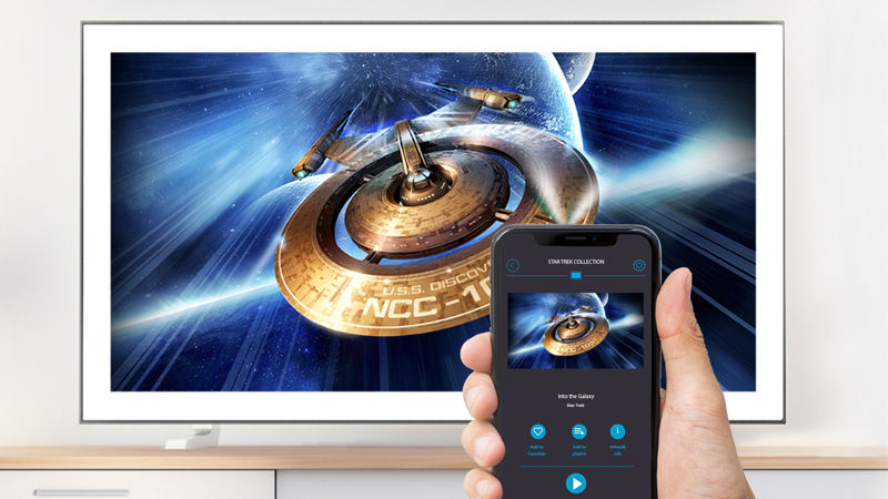 TV screen showing spaceship and a close-up of a palm holding a mobile phone