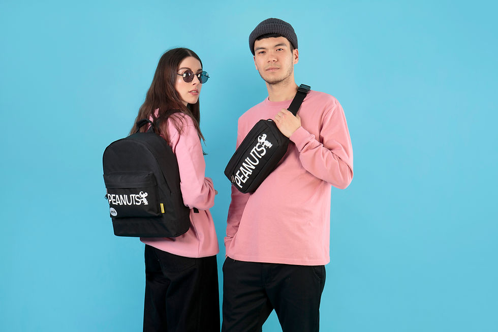 a woman and a man wearing matching pink/black outfits and wearing Peanuts branded backpacks