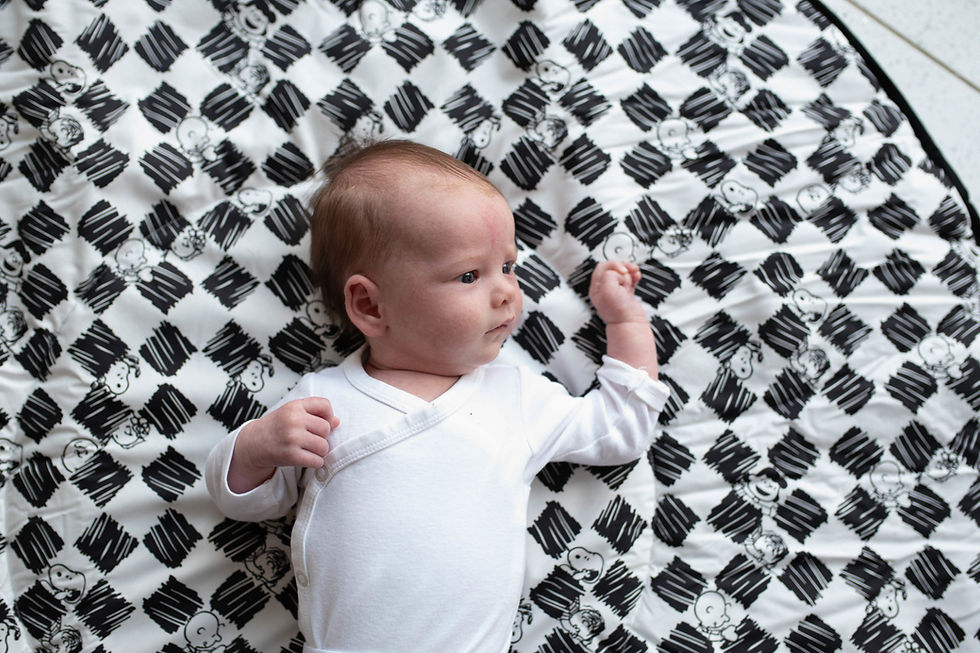 A baby is lying on a checkered blanket