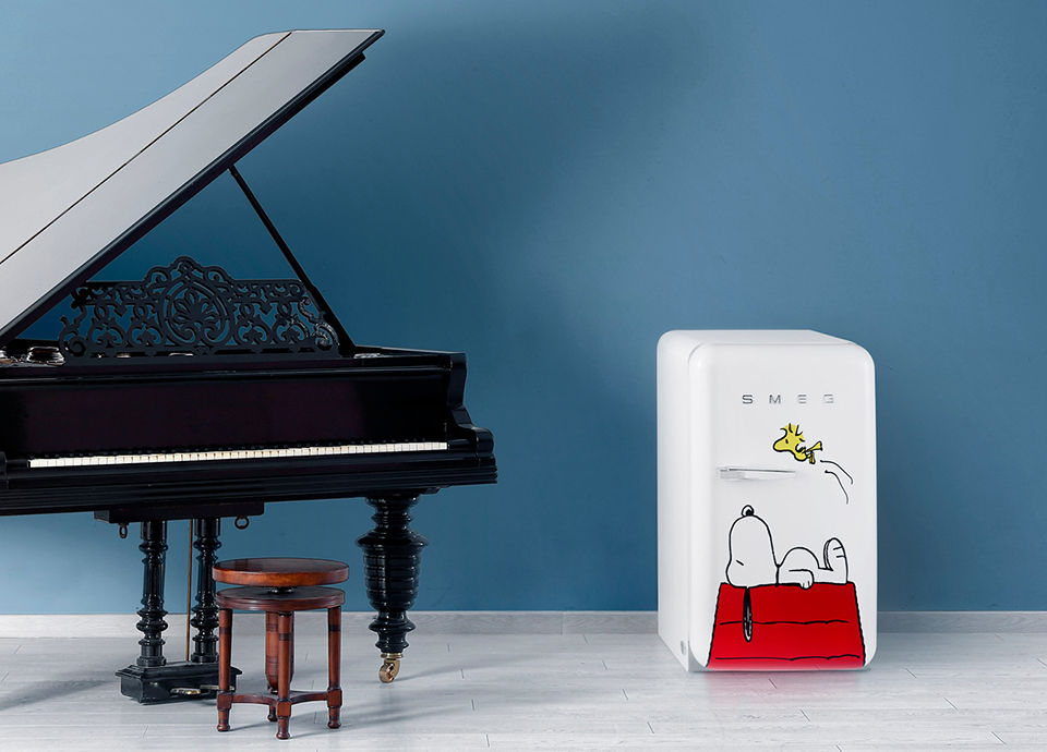 A grand piano and a white small fridge, decorated with a dog picture