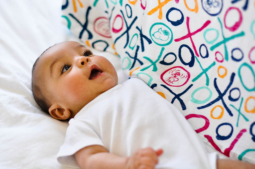 A baby is lying on a blanket with decorated with dog and a bird