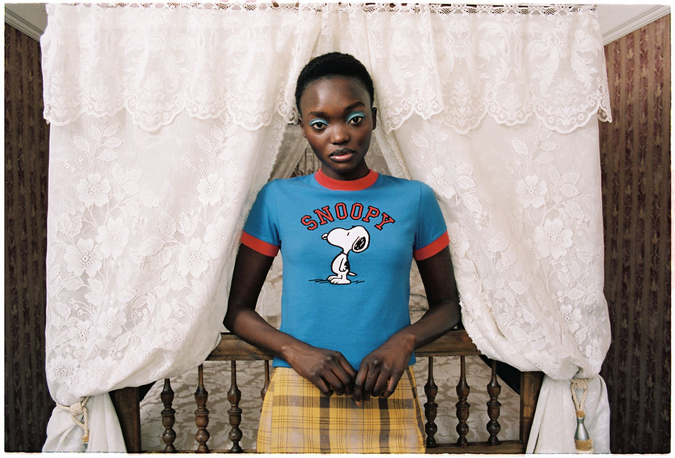 a woman model is posing in front of a bed with curtains, wearing blue t-shirt with an image of a beagle