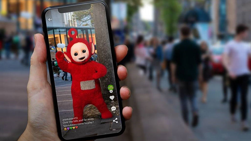 smartphone screen in a palm with a red alien like creature