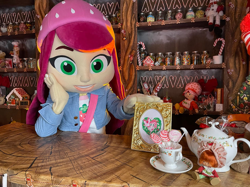 A fruit-themed costumed character stands near Strawberry Shortcake-themed products behind a wooden-painted bar.