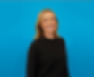 A headshot of a woman in a black shirt smiling and standing in front a blue background.