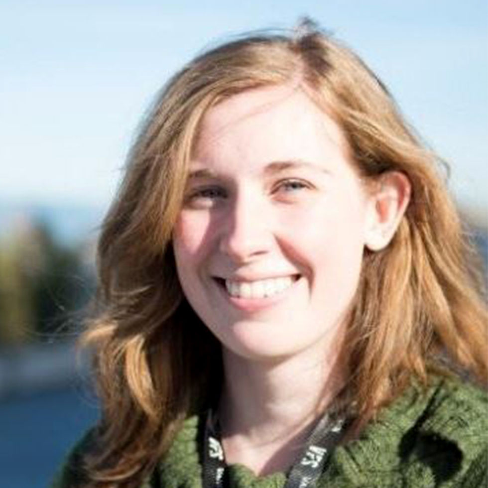 closeup of a blond-brown haired woman in a green coat posing for a photo