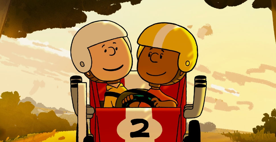 Charlie Brown and Franklin Armstrong smiling at each other as they sit in a soapbox car.