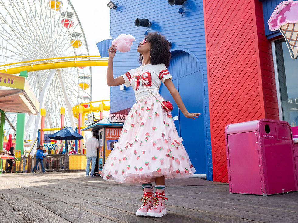 a black woman wearing a pink skirt and boots holding cotton candy