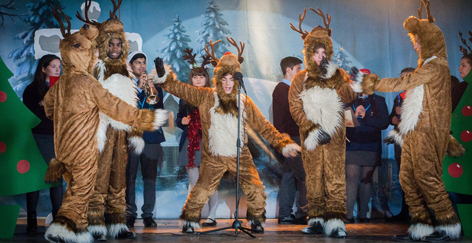 group of students in reindeer costumes on stage at a school