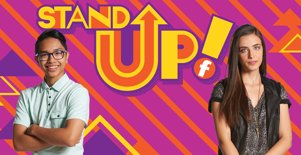 a young man and woman stand in front of a orange and purple background. "Stand Up" logo