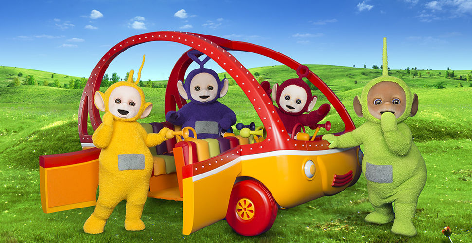 yellow, purple, red and green fuzzy creatures surround a red and orange vehicle in a meadow